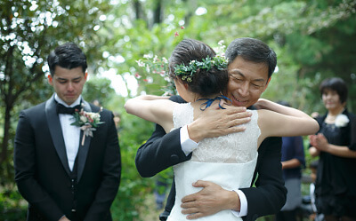 父親と抱き合う新婦と涙ぐむ新郎