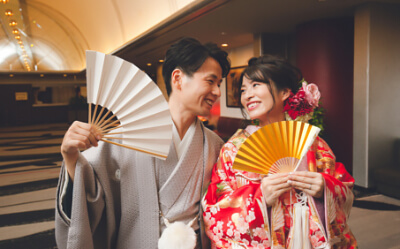 扇子を手に見つめ合う和装の新郎新婦